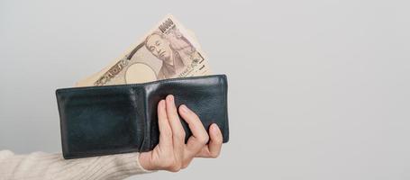 Woman hand holding Japanese Yen banknote with wallet. Thousand Yen money. Japan cash, Tax, Recession Economy, Inflation, Investment, finance and shopping payment concepts photo