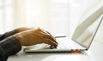 Close up of man hands using laptop at home office. Concept of searching web, browsing information. soft focus photo