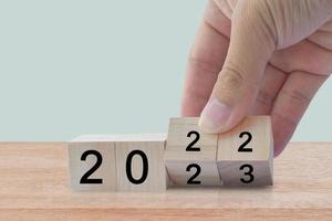 New year 2022 change to 2023. Hand flip over wooden cube block. New year holiday concept photo