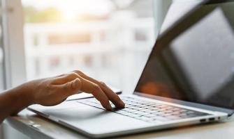 Close up of man hands using laptop at home office. Concept of searching web, browsing information. soft focus photo