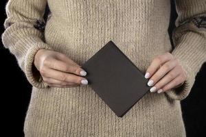 A brown leather wallet is in women's hands. photo