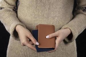 In female hands there is a brown purse and a passport. photo