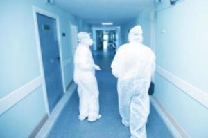 Blurred background of hospital corridor with doctors in protective suits. photo