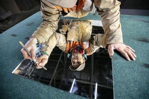 A worker cuts glass with a glass cutter. Furniture manufacturing. photo