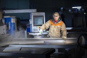 A furniture production worker behind a programmed machine makes furniture parts. Furniture manufacturing. photo