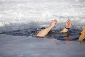 un hombre se sumerge dentro un pozo de hielo durante el invierno festival de el bautismo de Jesús. un hombre nada en el pozo de hielo en invierno. morsa gente. foto