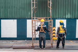 construcción trabajador vistiendo la seguridad arneses con andamio a construcción sitio. trabajando a alturas encima suelo ,seguro trabajando para andamio concepto foto