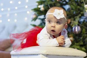 pequeño bebé a Navidad. tres meses de edad niña en contra el antecedentes de el Navidad árbol decoración. foto