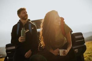 Young couple relaxing on a terrain vehicle hood at countryside photo