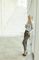 mujer de negocios que usa teléfono móvil en el pasillo de la oficina moderna foto
