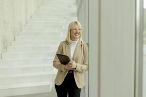 Businesswoman with digital tablet on modern office hallway photo