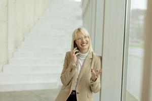 Businesswoman using mobile phone on modern office hallway photo