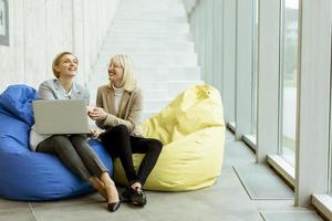 mujeres de negocios que usan computadoras portátiles en bolsas perezosas en la oficina moderna foto