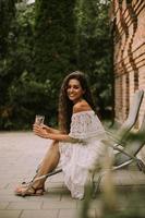 A young woman with curly hair relaxes on a deck chair and enjoys a glass of fresh lemonade photo