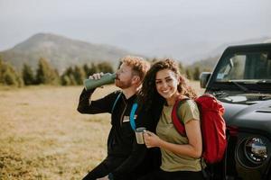 Smiling couple preparing hiking adventure with backpacks by terrain vehicle photo