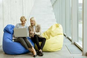 mujeres de negocios que usan computadoras portátiles en bolsas perezosas en la oficina moderna foto