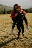 Young woman riding piggyback on a boyfriend at green hills photo