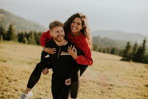 Young woman riding piggyback on a boyfriend at green hills photo