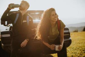 Young couple relaxing on a terrain vehicle hood at countryside photo