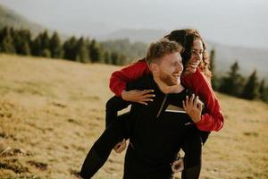 Young woman riding piggyback on a boyfriend at green hills photo