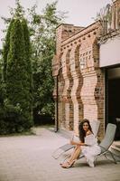 A young woman with curly hair relaxes on a deck chair and enjoys a glass of fresh lemonade photo