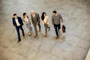 A group of young and senior business people are walking in an office hallway photo