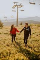 Smiling couple walking with backpacks over green hills photo