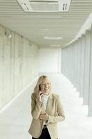 Businesswoman using mobile phone on modern office hallway photo