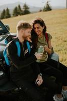 Young couple relaxing on a terrain vehicle hood at countryside photo