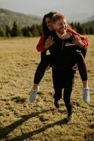 Young woman riding piggyback on a boyfriend at green hills photo