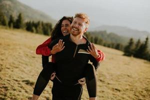 Young woman riding piggyback on a boyfriend at green hills photo