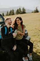 Young couple relaxing on a terrain vehicle hood at countryside photo