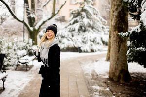 Young woman with Warm Clothes in Cold Winter Snow drinking coffee to go photo
