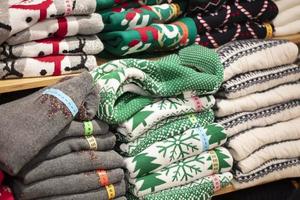 Sweaters with Christmas ornaments in the store.Stack of folded knitted photo