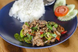 Stir Fried Basil with Stewed Pork on Rice popular traditional Thai food with wooden table background. side view photo