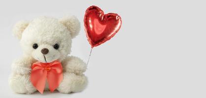 Cute teddy bear holds a heart ball. Valentine with a bear. photo