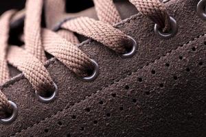 Part of a suede boot with laces. A fragment of brown shoes. A piece of sneaker. photo