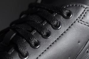 Part of a black boot with laces. A fragment of dark shoes. A piece of sneaker. photo