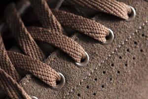 Part of a suede boot with laces. A fragment of brown shoes. A piece of sneaker. photo