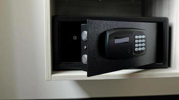 Metal safe box in the closet. Small narrow safe for keeping money or valuables in the hotel. Open safe door with buttons for entering a password. Compact strongbox inside cabinet. Empty safe. photo