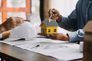 Image of engineering objects on workplace with three partners interacting on background photo
