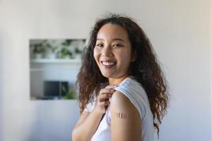 joven asiático mujer con adhesivo vendaje en su brazo después corona virus vacuna. primero ayuda. médico, farmacia y cuidado de la salud concepto. foto