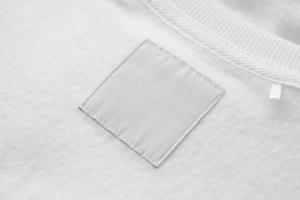 Blank white laundry care clothes label on fabric texture background photo