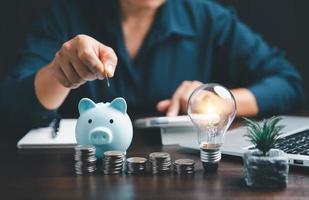 Businesswoman with lightbulb and piggy bank and using calculator to calculate and money stack. Save energy and money with accounting finance in office concept. Idea of energy saving planning in home. photo