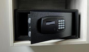 Metal safe box in the closet. Small narrow safe for keeping money or valuables in the hotel. Open safe door with buttons for entering a password. Compact strongbox inside cabinet. Empty safe. photo