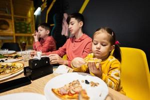 cuatro niños comiendo italiano Pizza en pizzería. niños comer a cafetería. foto