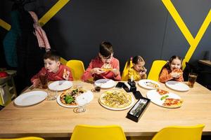 cuatro niños comiendo italiano Pizza en pizzería. niños comer a cafetería. foto
