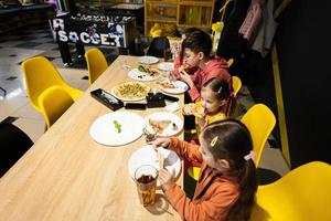 Four kids eating italian pizza in pizzeria. Children eat at cafe. photo