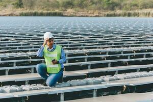 Engineer inspector holding laptop and working in solar panels power plant checking photovoltaic cells and electricity production. photo