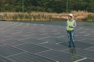 Engineer inspector holding laptop and working in solar panels power plant checking photovoltaic cells and electricity production. photo